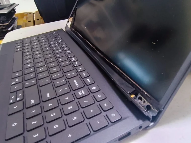 Bisagra y carcasa fracturadas de laptop, con conectores internos expuestos junto al teclado